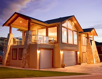 A new 2-story well-lit modern home at dusk with a covered deck